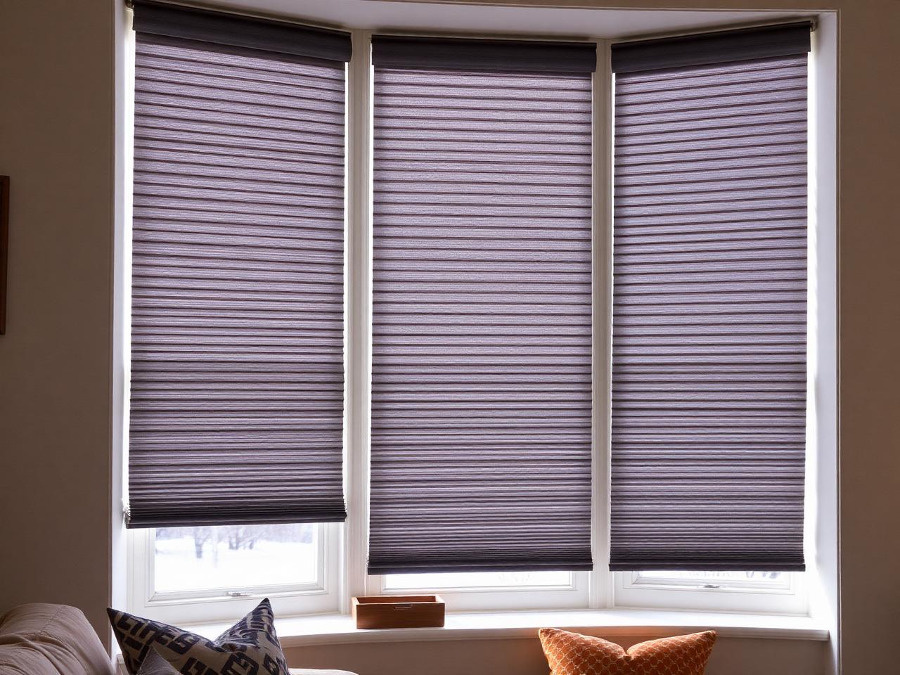 Cellular honeycomb shades fitted across a bay window in a family room