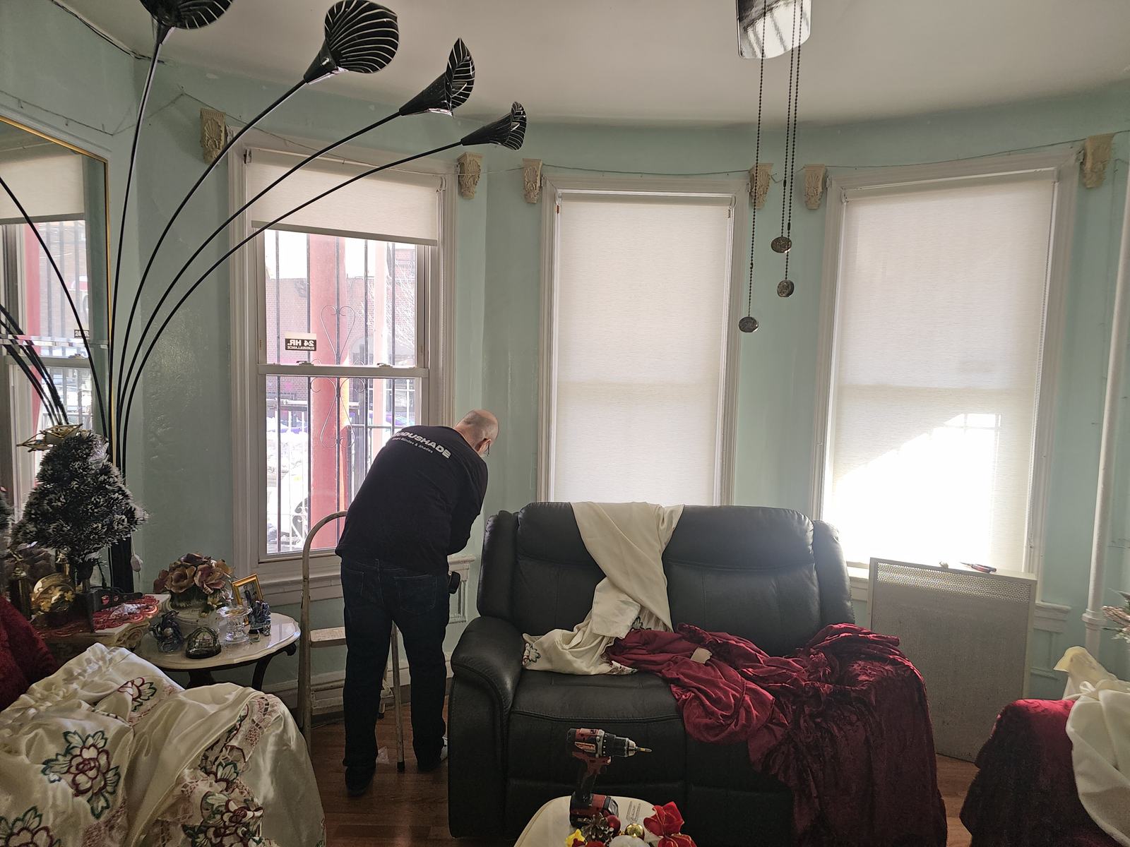 ModuShade installer adjusting a newly fitted shade in a bay window
