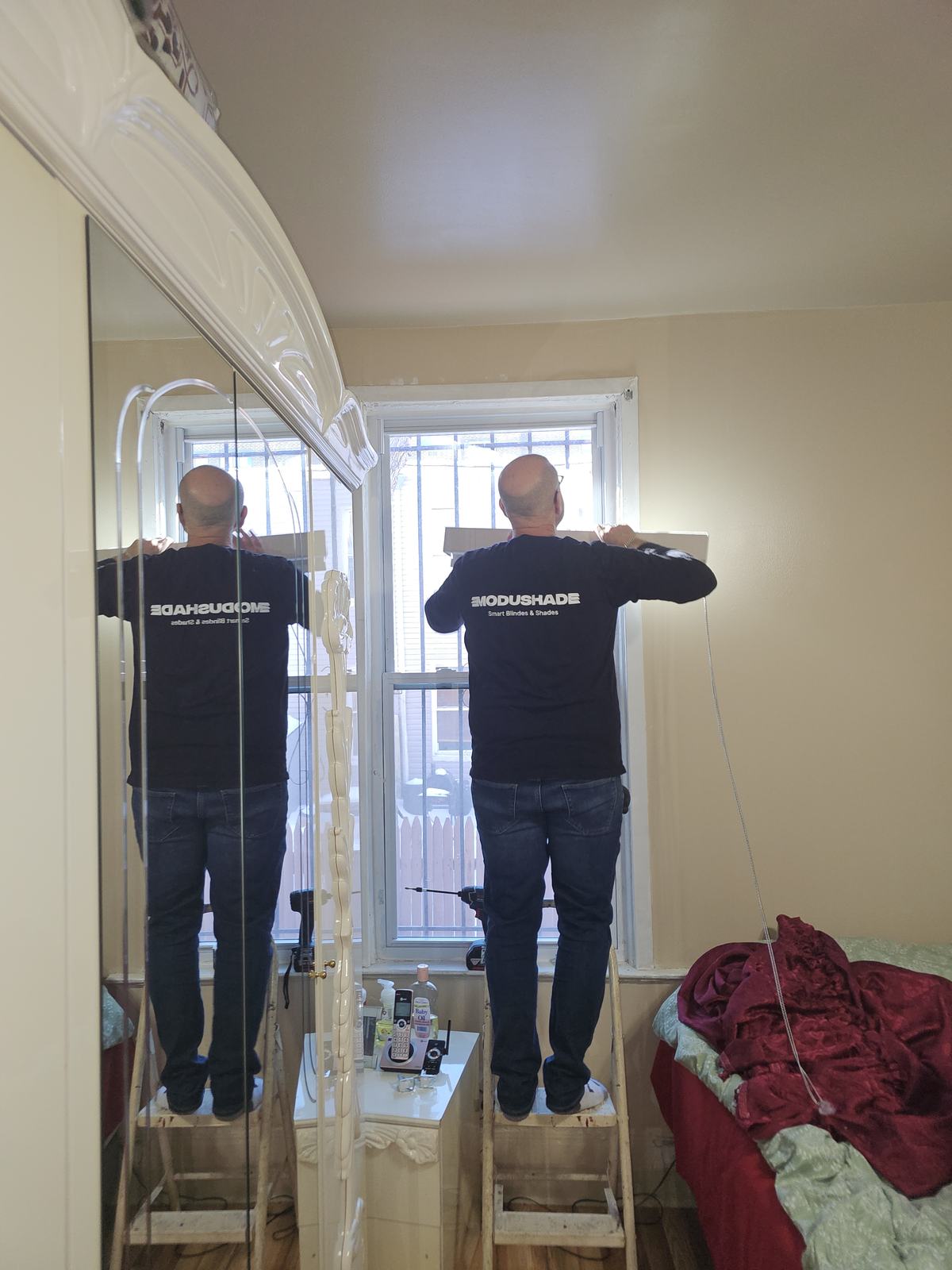 ModuShade installers on ladders fitting shades at a tall arched window