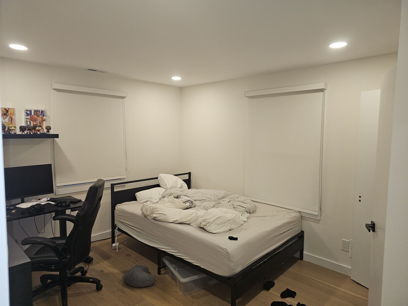 Roller shade half raised above a desk in a bedroom used as a home office