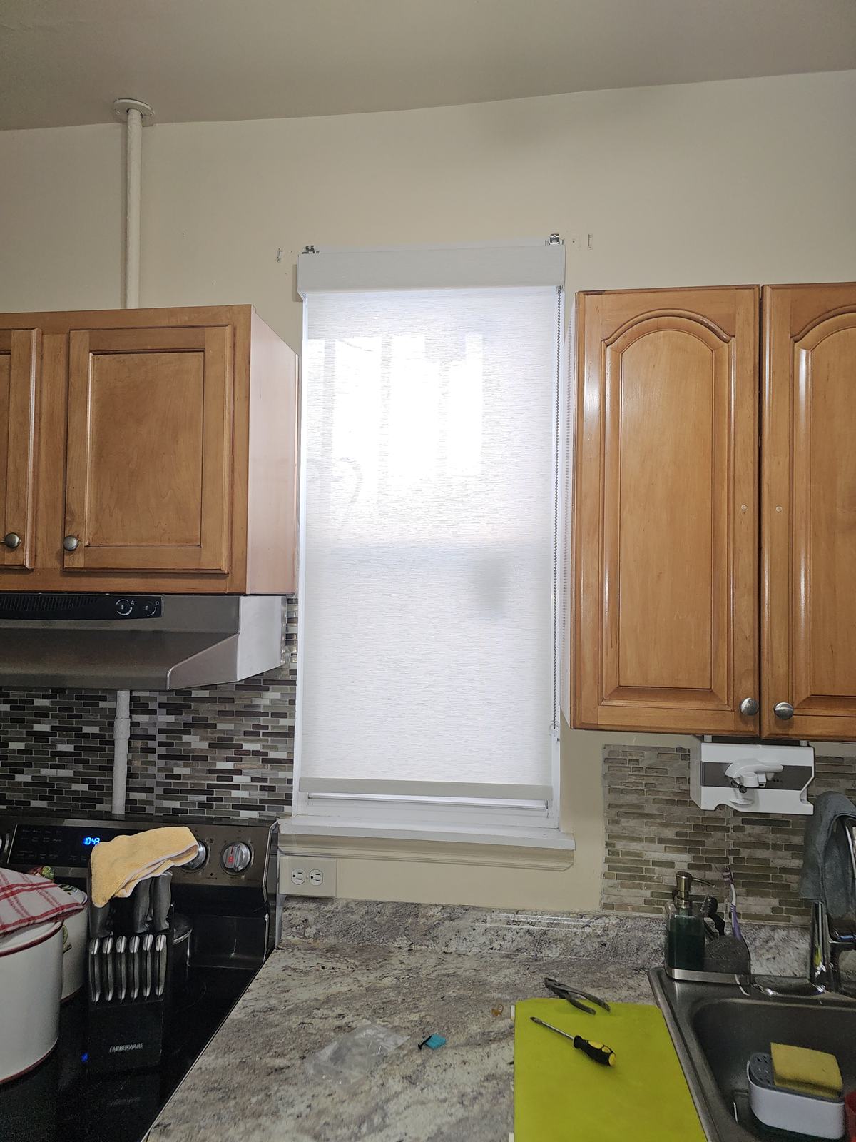 Roller shade fitted above a kitchen window beside cabinetry in a suburban New Jersey home