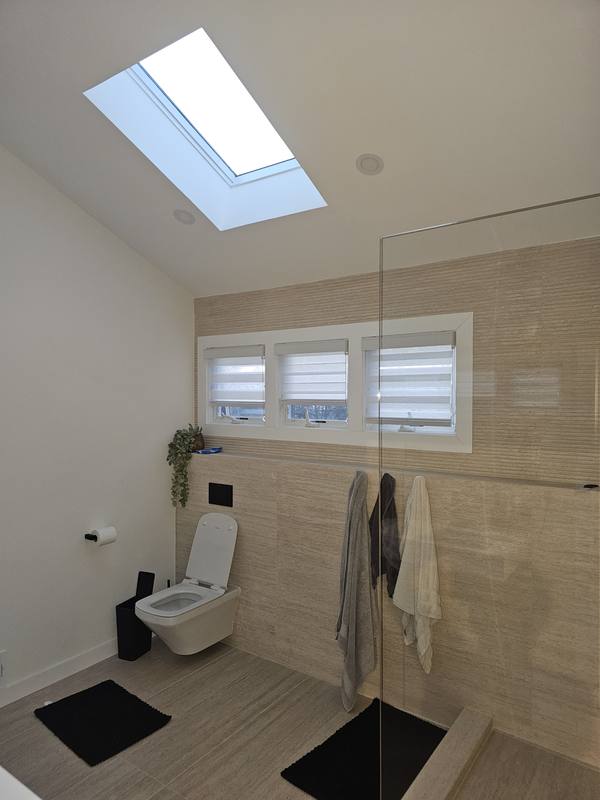 Light filtering shade fitted to a bathroom window under a sloped ceiling