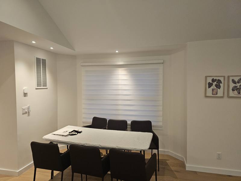 Zebra shades across a dining area window wall with a table and chairs in front