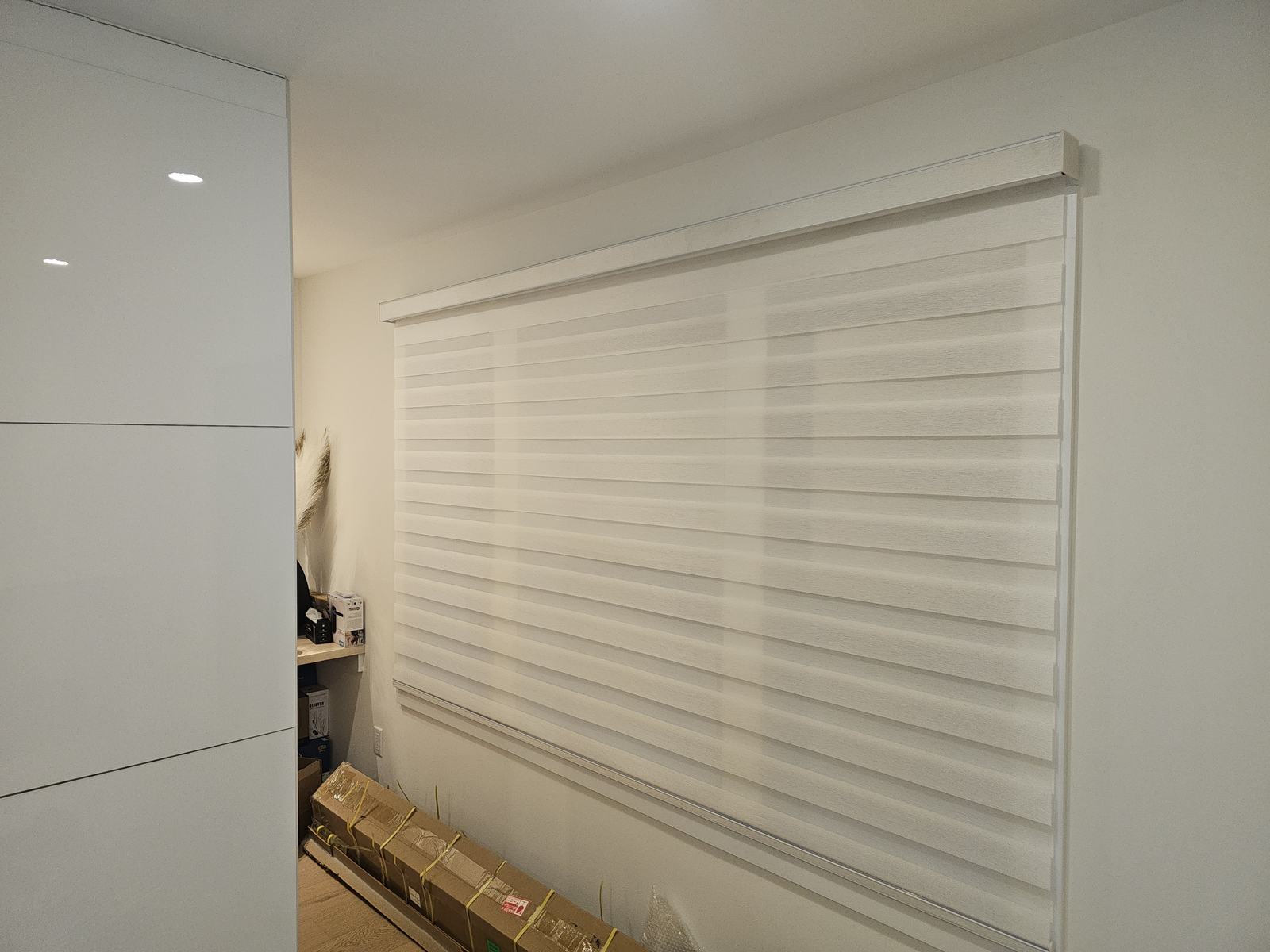ModuShade zebra shade lowered across a wide bedroom window, sheer and solid bands aligned