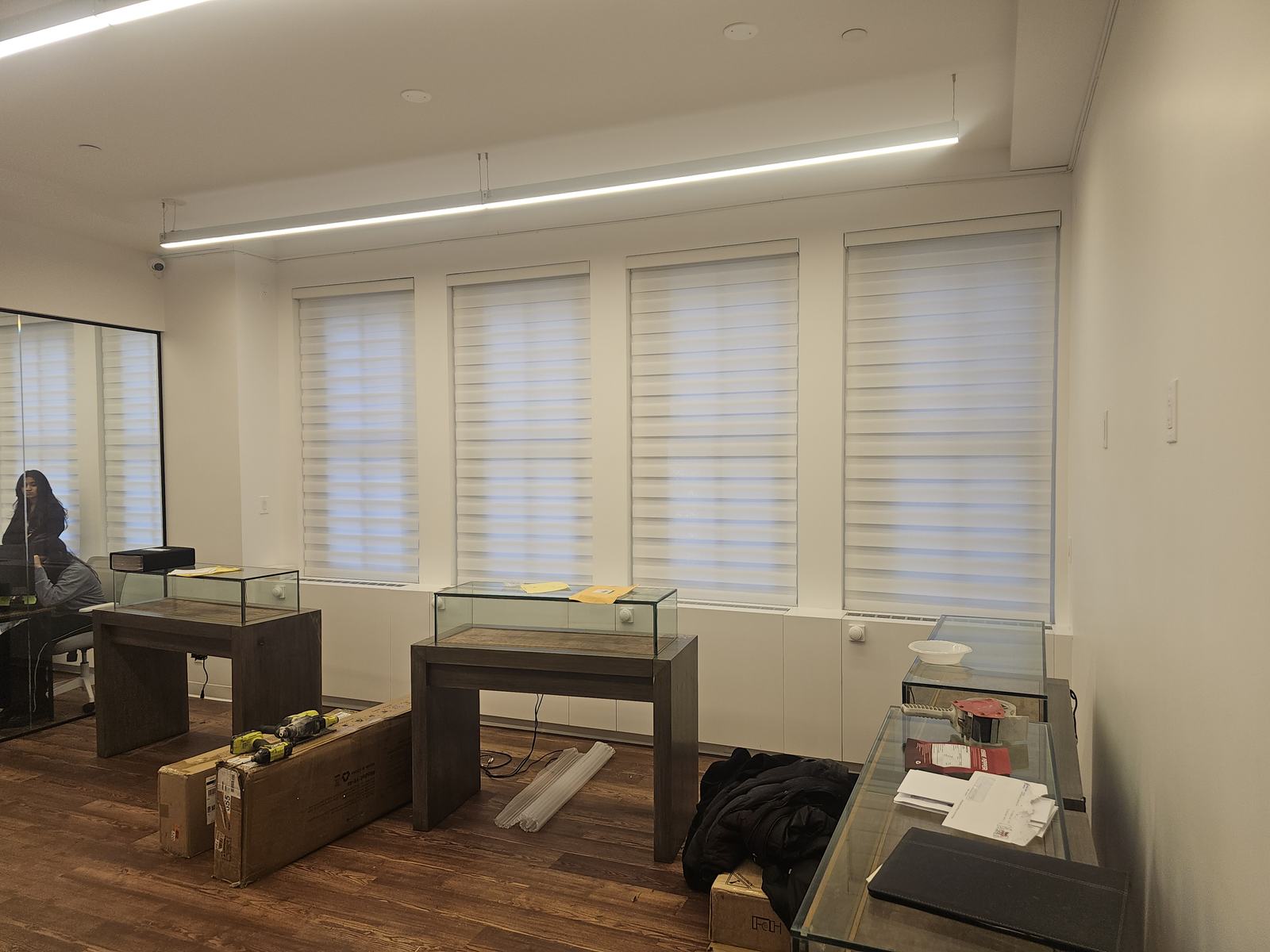 Zebra shades along a showroom window wall with display cases below, cutting glare at street level
